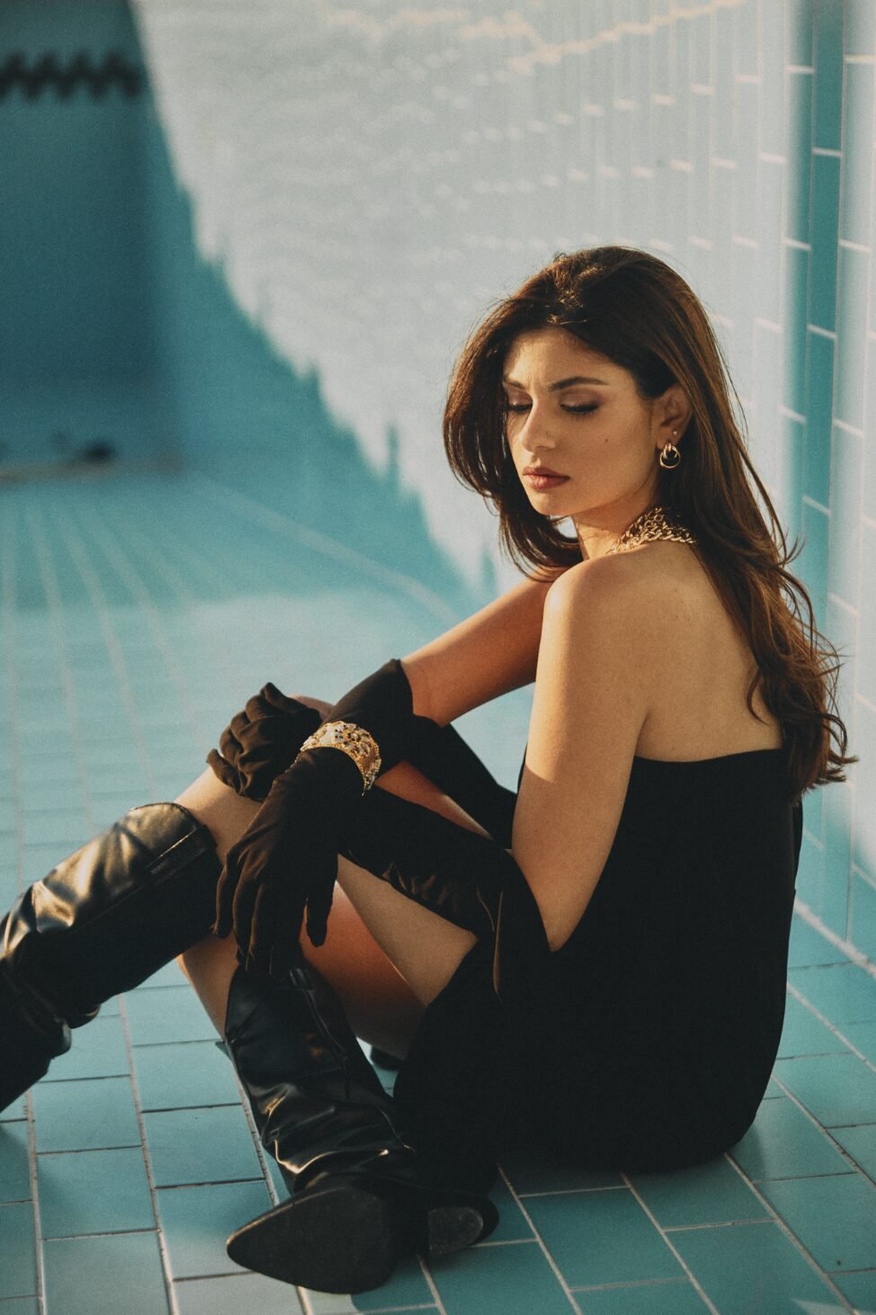 High-fashion editorial portrait of actress Joan Zaybak seated poolside wearing a black dress and statement gloves, photographed by film director and fashion photographer Jean-Claude Dib